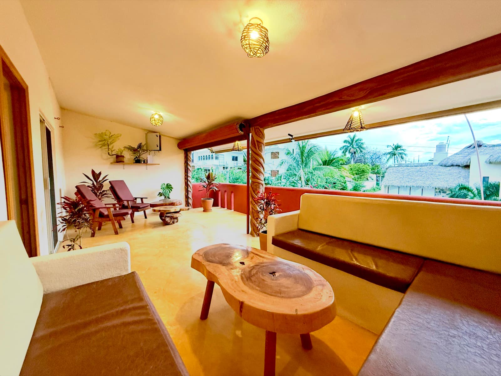 Casa Bel's open-air rooftop patio with lounge seating, natural wood coffee table, and palm tree views at Punta Ox Ha in Puerto Escondido